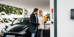 Billede af et par og deres nye elbil hjemme i garagen.